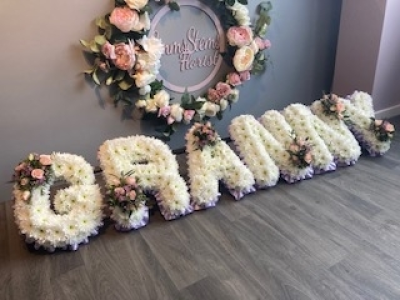 GRANNY - GRANNY - Arranged with a lovely lilac ribbon edge, white base flowers and soft pink roses in the letter sprays. GRANNY - GRANNY - Arranged with a lovely lilac ribbon edge, white base flowers and soft pink roses in the letter sprays.