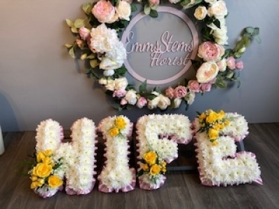 Yellow Wife Letters - Wife letter tribute, arranged with a Pink ribbon edge, white based flowers and yellow letter sprays. These can be arranged in your own choice of colours. Yellow Wife Letters - Wife letter tribute, arranged with a Pink ribbon edge, white based flowers and yellow letter sprays. These can be arranged in your own choice of colours.
