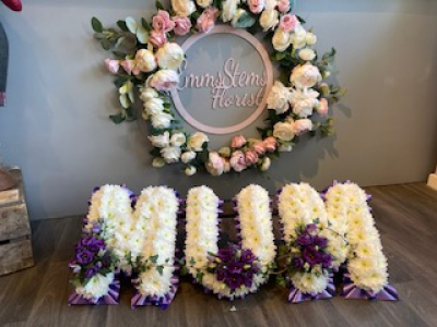 MUM - Mum, based in white with purple ribbon and flower sprays MUM - Mum, based in white with purple ribbon and flower sprays